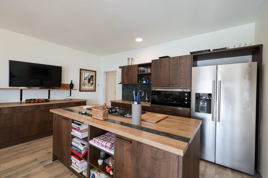 Druga elewacja kuchenna z drewnianymi frontami szafek i nowoczesnym sprzętem w willi na sprzedaż na wyspie Ugljan