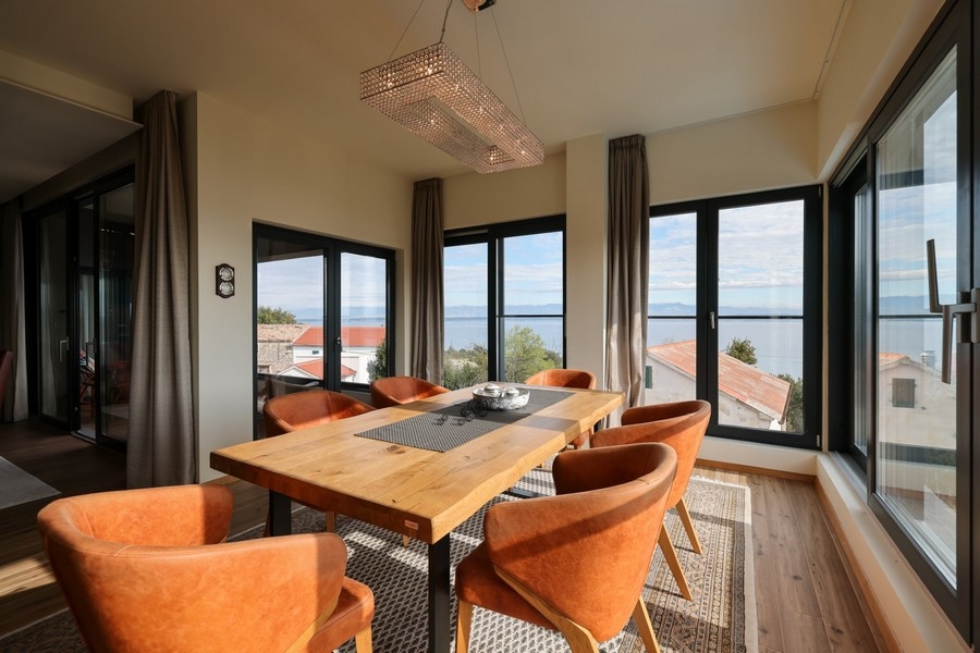 Jadalnia z drewnianym stołem, pomarańczowymi krzesłami i widokiem na morze w willi na sprzedaż na Ugljan.