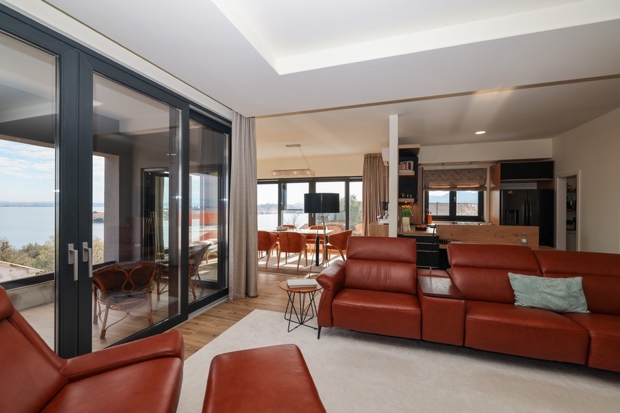 Pokój dzienny ze skórzaną sofą w kształcie litery L i otwartym przejściem do kuchni w willi na Ugljan, która jest na sprzedaż