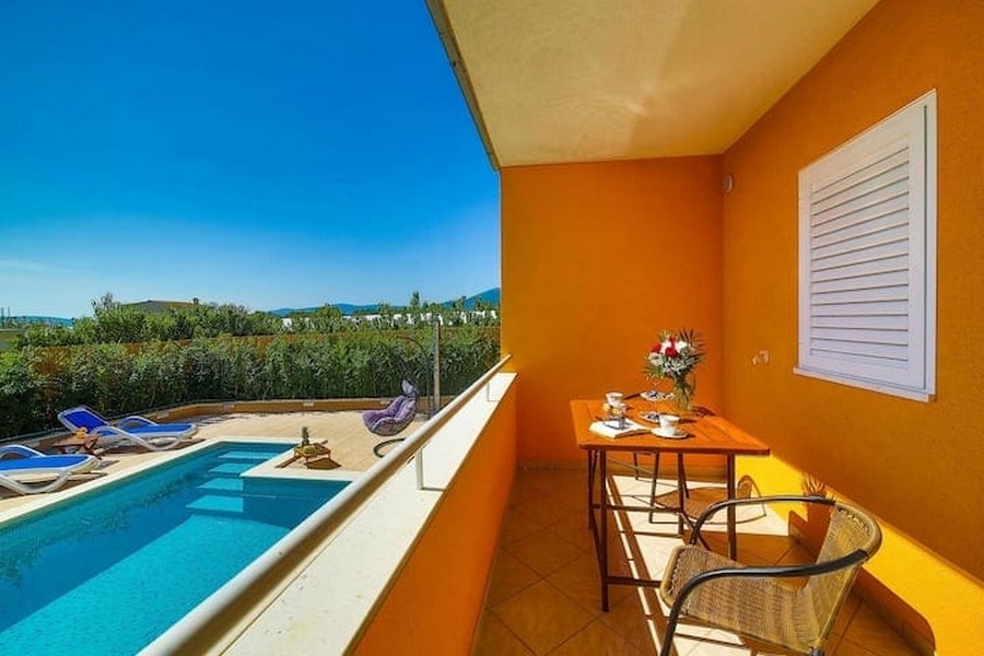 Widok z balkonu na basen budynku mieszkalnego w Kaštel Lukšić w Chorwacji, ze stołem i krzesłami