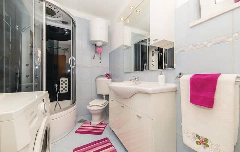 Łazienka z kabiną prysznicową i pralką w apartamentowcu w Kaštel Lukšić w Chorwacji