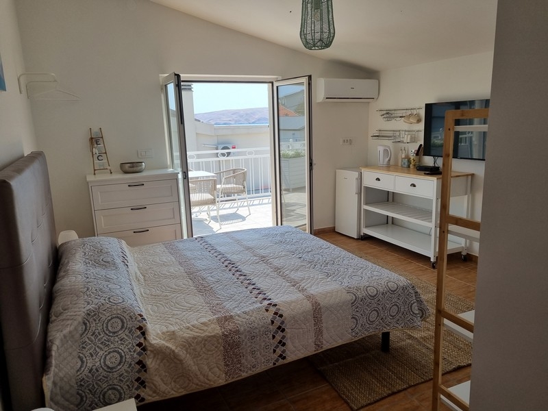 Jasny apartament typu studio z podwójnym łóżkiem, zintegrowaną kuchnią i drzwiami balkonowymi z widokiem na morze, na sprzedaż w Karlobag w Chorwacji, część apartamentowca tuż nad morzem.