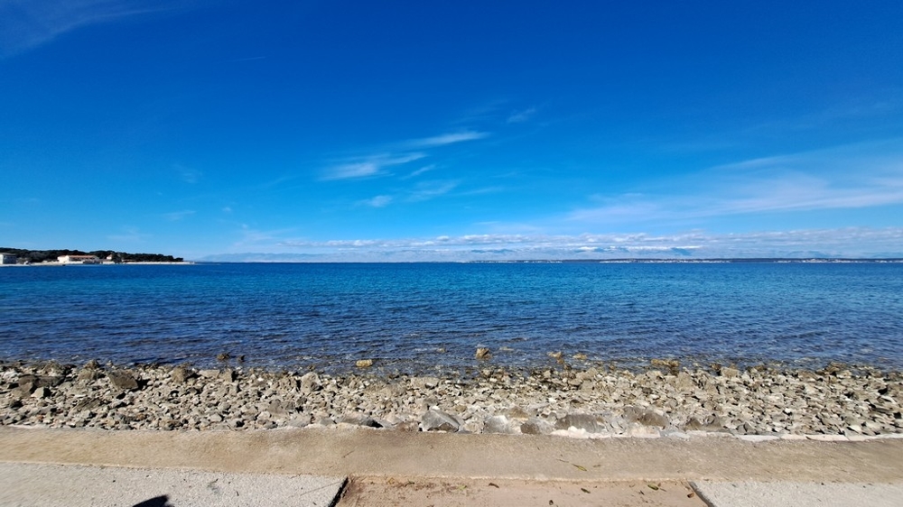 Żwirowa plaża i czyste morze przed posiadłością nad morzem w Chorwacji
