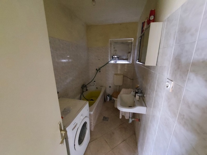 Częściowo wykończona łazienka w domu na sprzedaż w Diklo w Chorwacji, z pralką i elementami budowlanymi