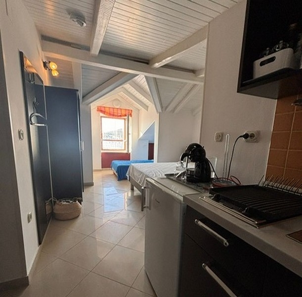 Kompaktowy aneks kuchenny z przylegającą częścią sypialną w chorwackiej posiadłości. 4 stół jadalny z widokiem na scenę mariny przez okno nieruchomości w Chorwacji