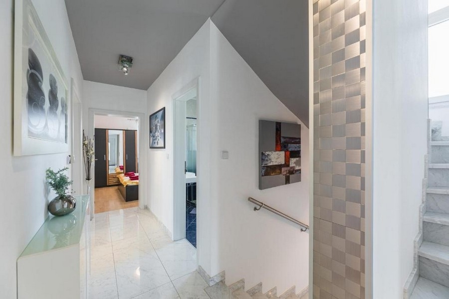 Strefa wejściowa i korytarz budynku mieszkalnego w Chorwacji z widokiem na morze, z błyszczącymi płytkami podłogowymi, schodami i dekoracjami ściennymi