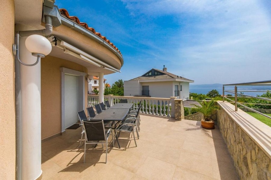Duży taras budynku mieszkalnego w Chorwacji z długim stołem i krzesłami, widok na morze