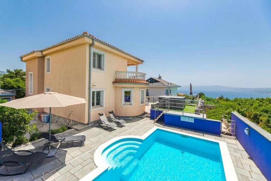 Podwórko apartamentowca w Chorwacji z basenem i leżakami, widok na morze