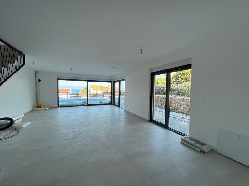 Część dzienna z wyraźnym widokiem na zewnątrz i otwartymi schodami, charakterystyczna dla nowoczesnych nieruchomości w Chorwacji.