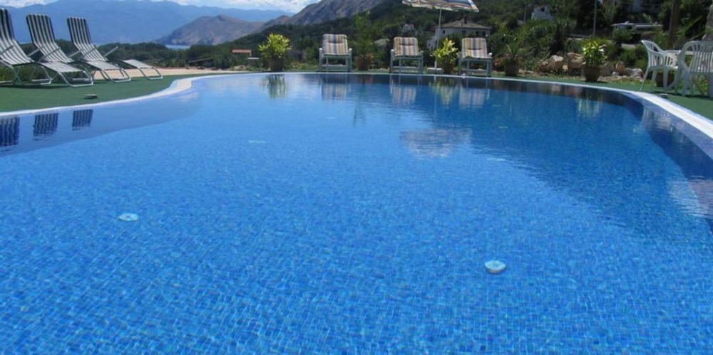 Niebieski basen z widokiem na góry otoczony leżakami, nieruchomość w Chorwacji