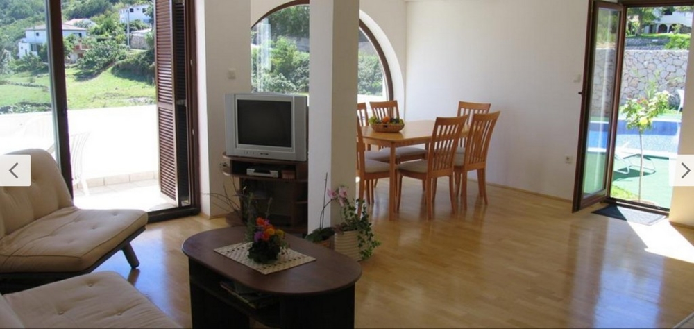 Widok wnętrza jasnego salonu z drewnianymi podłogami i dostępem do basenu, nieruchomość Chorwacja