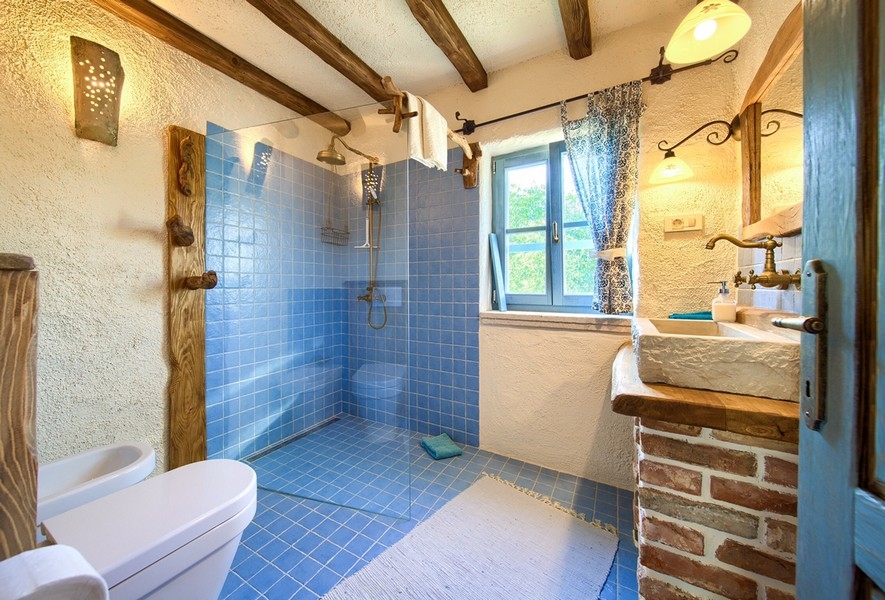 Łazienka z niebieskimi kafelkami i elementami z naturalnego drewna oferuje nowoczesny komfort w posiadłości na wyspie Krk.