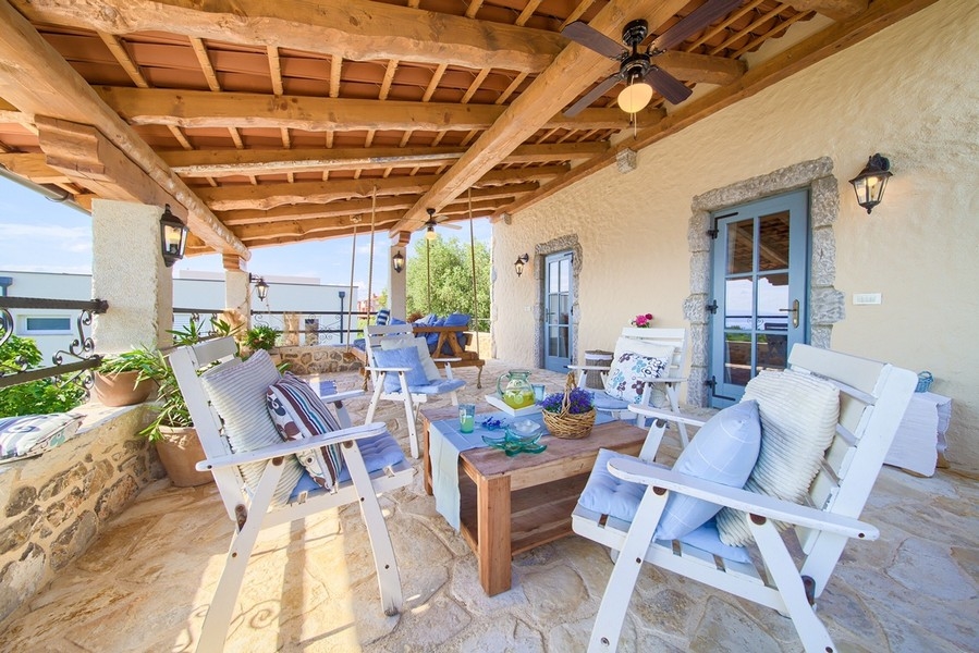 Zapraszający taras z rustykalnymi drewnianymi meblami i brukowaną podłogą, charakterystyczny dla nieruchomości na wyspie Krk.