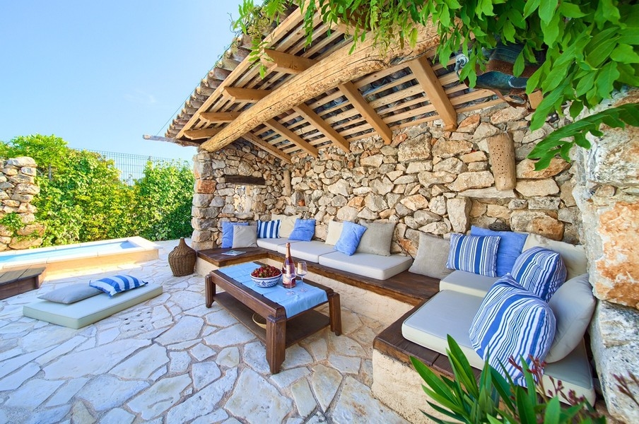 Zadaszona część wypoczynkowa na świeżym powietrzu z wygodnymi poduszkami i widokiem na basen, typowym dla nieruchomości na wyspie Krk.