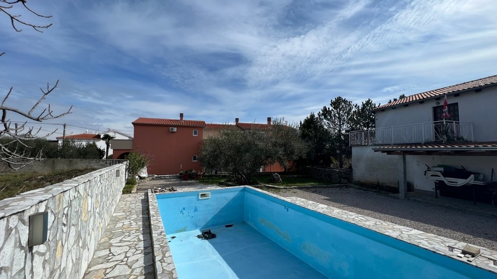 Nieruchomości Chorwacja, miasto Krk, wyspa Krk Kupno budynku mieszkalnego, widok z tyłu domu z pustym basenem i ogrodem