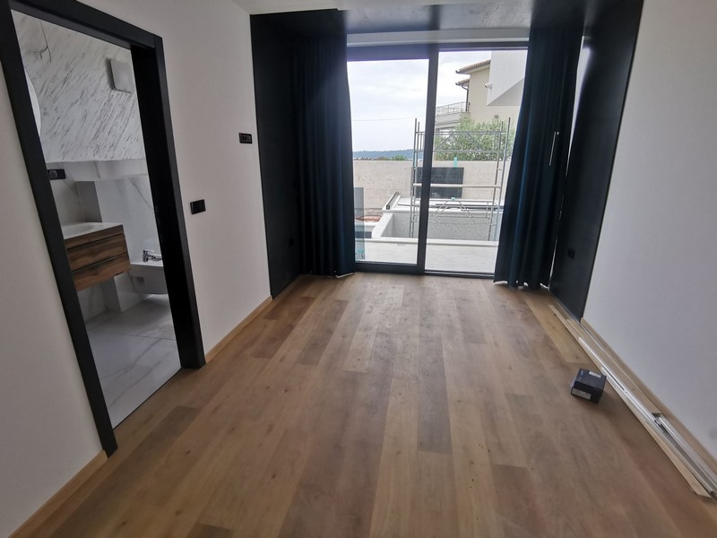 Widok wnętrza sypialni z drewnianymi podłogami i dużym oknem