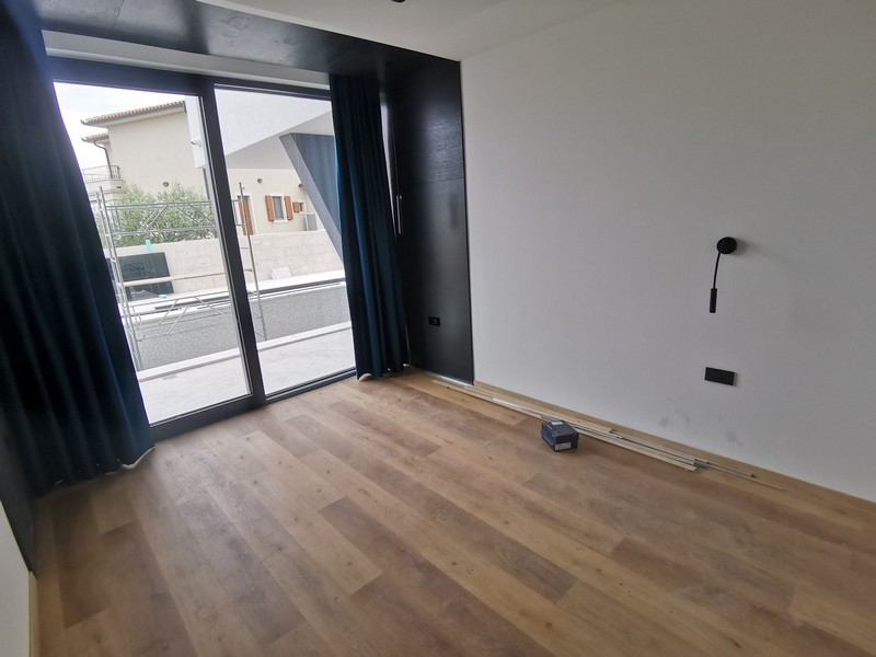 Widok wnętrza sypialni z drewnianymi podłogami i dużym oknem