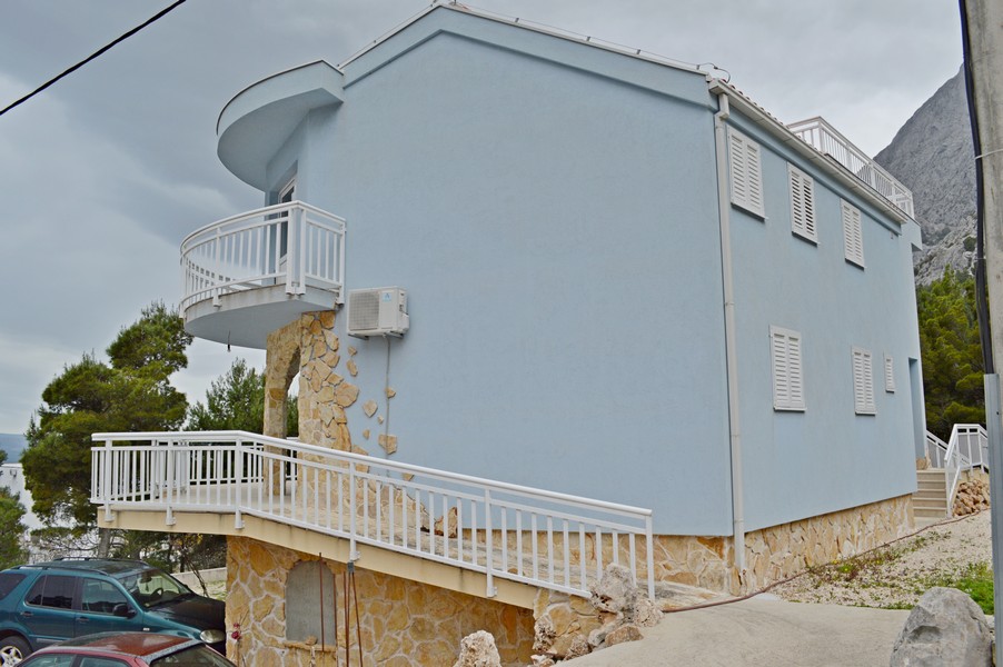 Niebieski dom z kamienną ścianą i balkonem