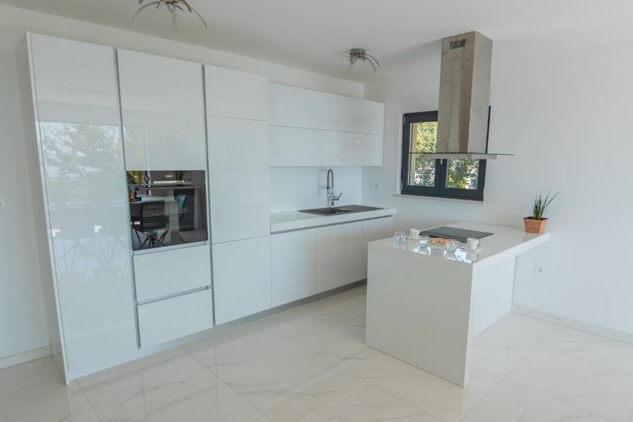 Nowoczesna kuchnia z białymi szafkami i wyspą na środku