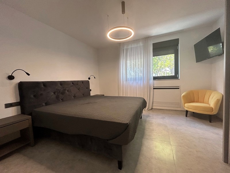 Przytulna sypialnia z fotelem i dużym oknem, które wpada dużo naturalnego światła