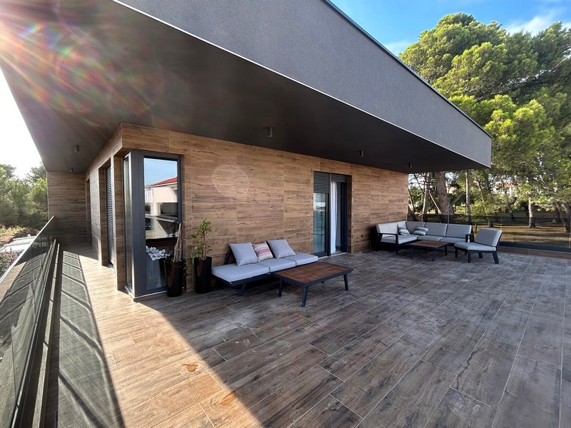 Duży taras willi z miejscami do siedzenia i widokiem na okoliczne drzewa