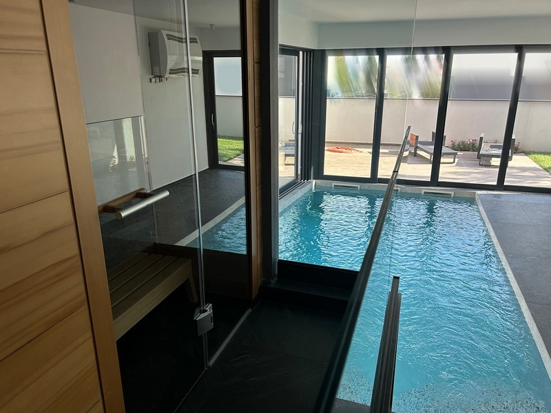 Kryty basen willi ze szklanymi ścianami łączącymi strefę basenową z ogrodem