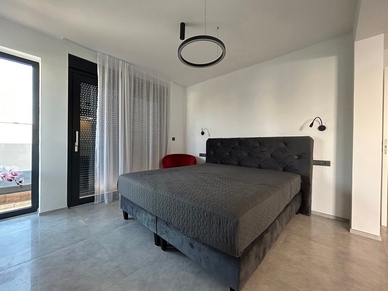 Sypialnia z bezpośrednim wyjściem na taras i minimalistycznym umeblowaniem