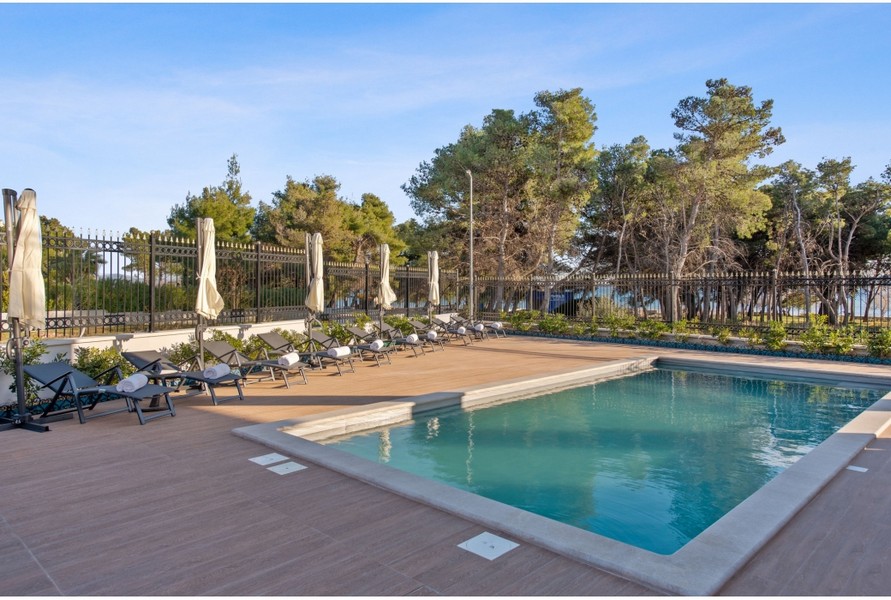 Teren zewnętrzny willi H3042 z podgrzewanym basenem zewnętrznym i leżakami otoczonymi śródziemnomorską roślinnością