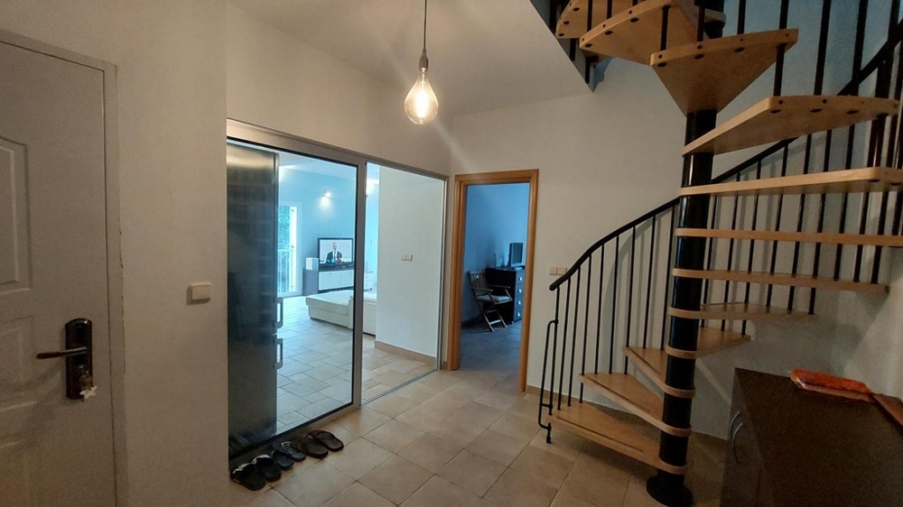 Strefa wejściowa ze spiralnymi schodami i widokiem na salon w domu w Chorwacji