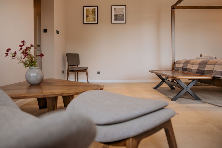 Nowoczesna i elegancka sypialnia z biurkiem, telewizorem naściennym i dużym lustrem, z delikatnym oświetleniem i neutralnymi tonami