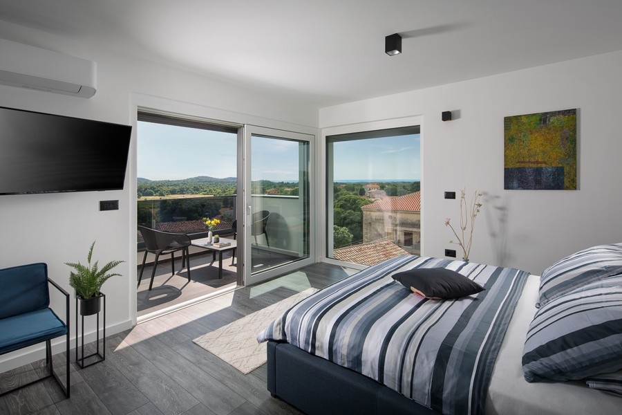 Sypialnia z widokiem na zieloną okolicę i morze.