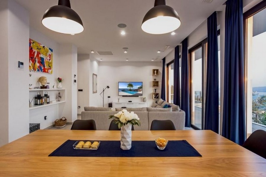 Pokój dzienny z dużą sofą, telewizorem z płaskim ekranem i widokiem na morze przez duże okna