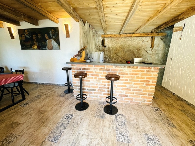 Rustykalna tawerna z ceglanym barem, stropem z belkami stropowymi i stołkami barowymi