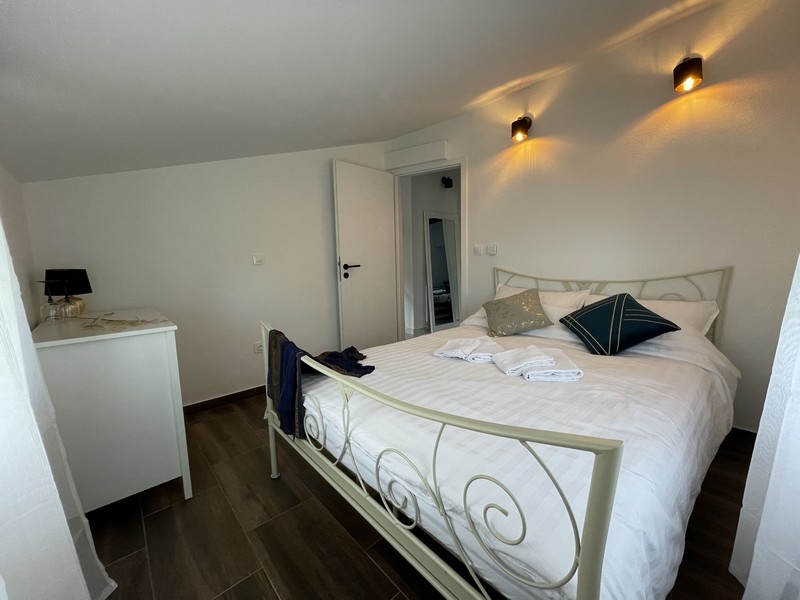 Sypialnia z białym łóżkiem z kutego żelaza, ozdobnymi poduszkami i nowoczesną atmosferą