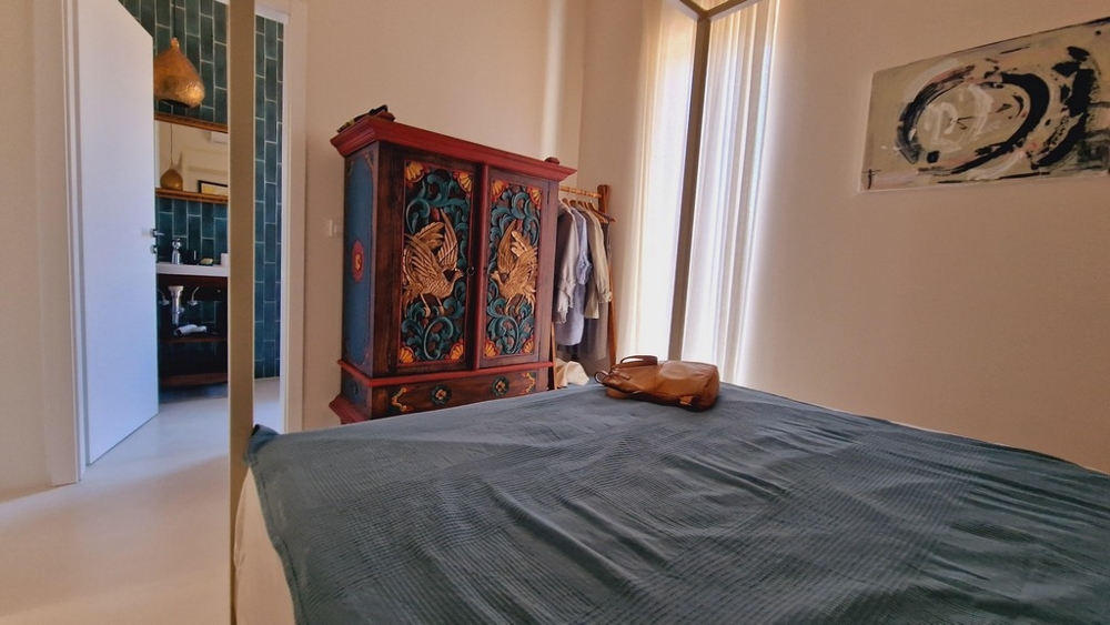 Sypialnia z rustykalną szafą i widokiem na sąsiednią łazienkę