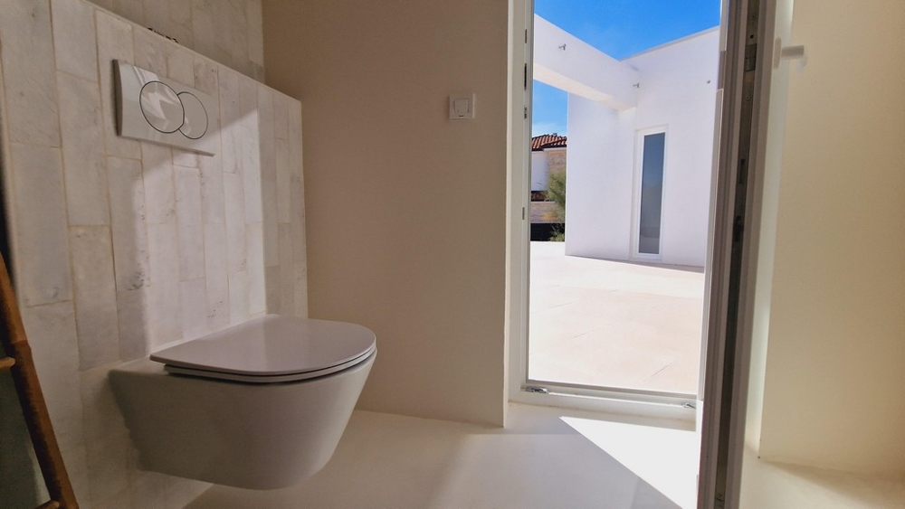 Druga łazienka ze ścianą z białych płytek i drzwiami na zewnętrzny taras