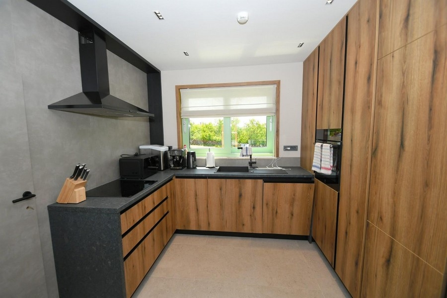 Nowoczesna kuchnia z boazerią, czarnymi blatami i sprzętem kuchennym