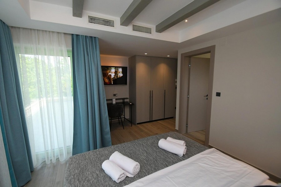 Sypialnia z dużymi oknami, niebieskimi zasłonami i nowoczesnym wnętrzem