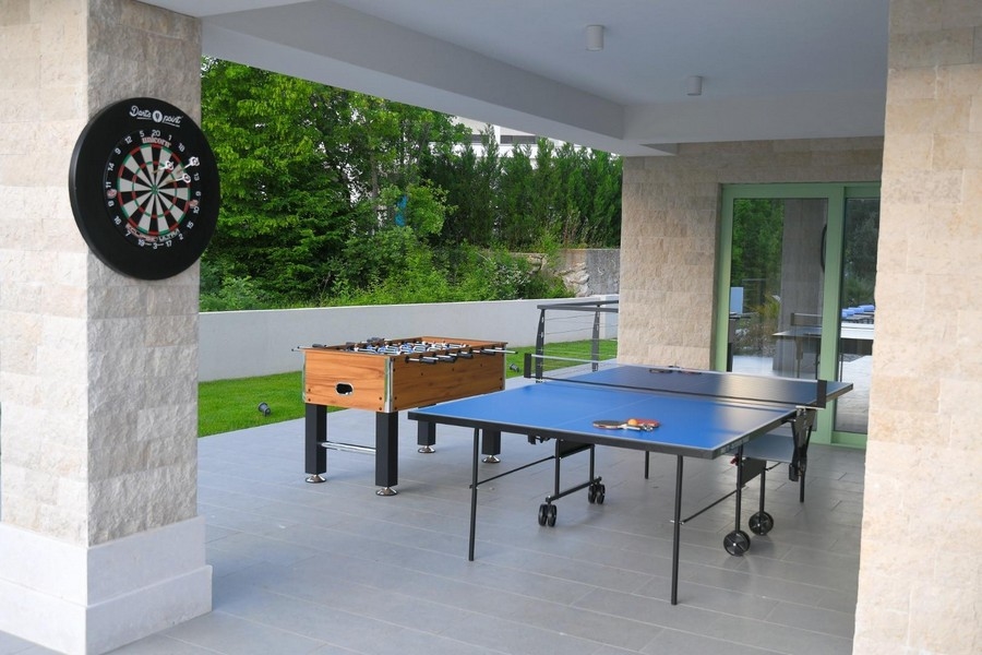 Zadaszony teren zewnętrzny ze stołem do tenisa stołowego, tarczą do darta i stołem do gry w piłkarzyki