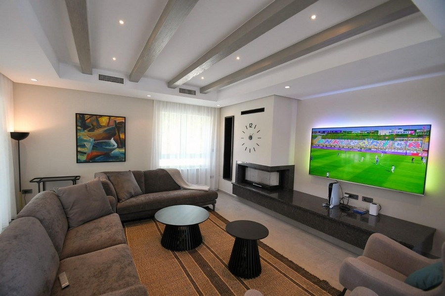 Nowoczesna część dzienna z dużym telewizorem i kominkiem.