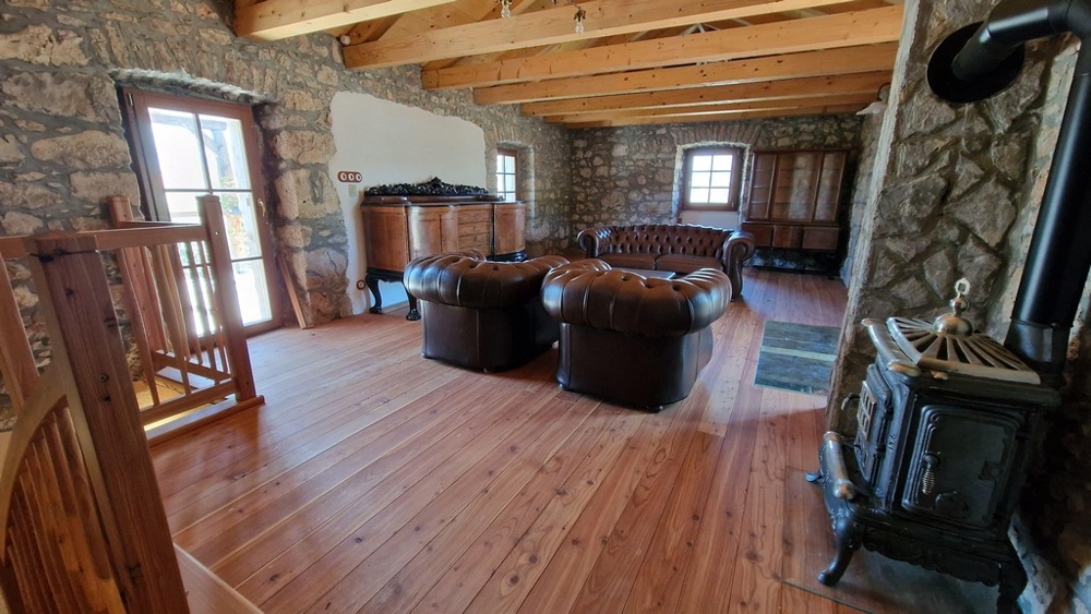 Duży salon na piętrze ze skórzanymi fotelami i piecem opalanym drewnem.