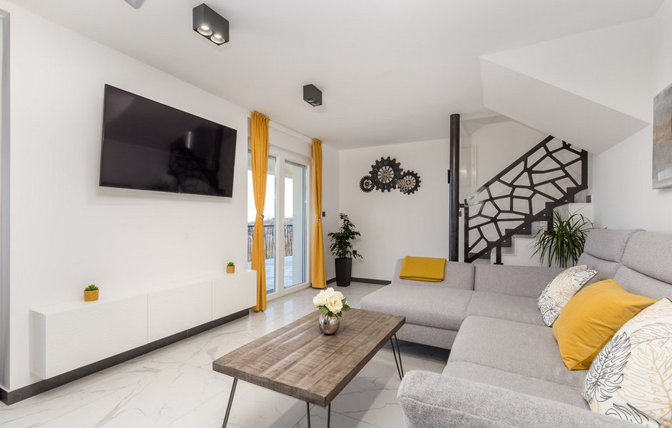 Nowoczesny salon z szarą sofą i żółtymi akcentami