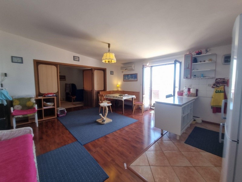 Otwarty salon z drewnianymi podłogami i bezpośrednim wyjściem na taras, wygodną częścią wypoczynkową i jadalną.