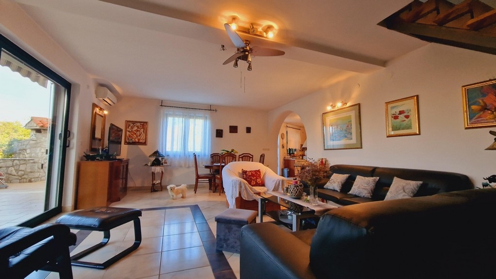 Pokój dzienny z wygodną sofą, szklanym stołem i dużym oknem wychodzącym na taras