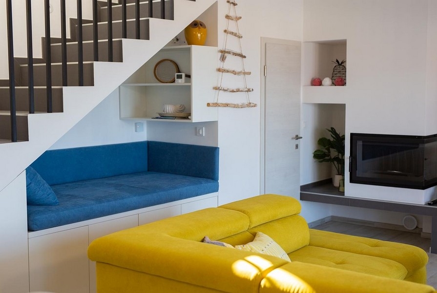 Pokój dzienny z żółtą sofą, niebieska część wypoczynkowa pod schodami, nowoczesny design