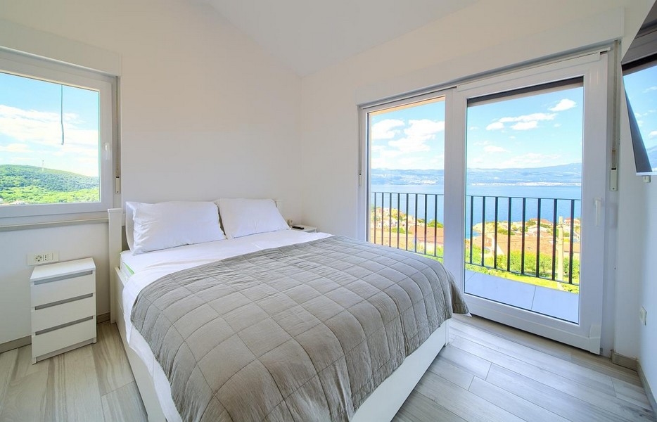 Sypialnia z podwójnym łóżkiem i drzwiami balkonowymi, w tle wspaniały widok na morze