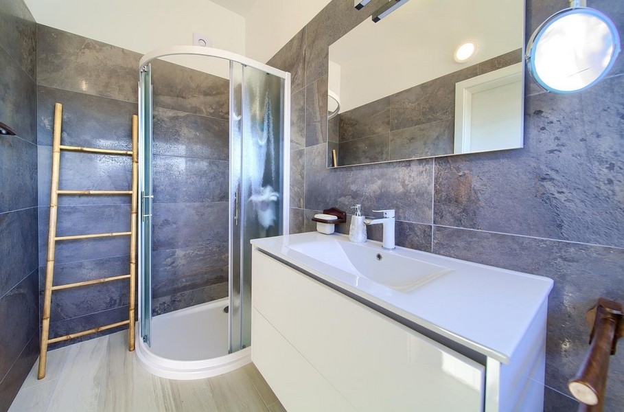 Nowoczesna łazienka z prysznicem, szarymi płytkami ściennymi i białą szafką podumywalkową