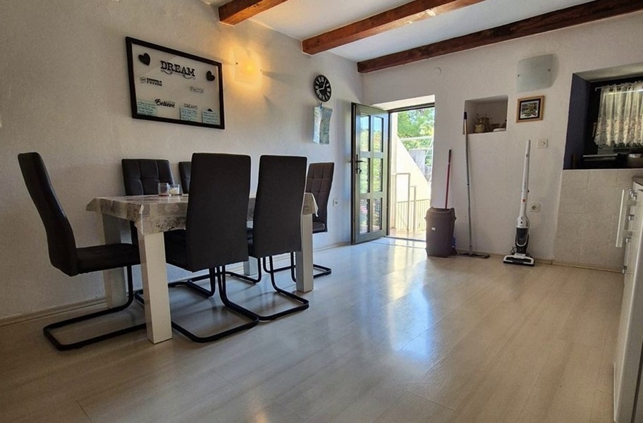 Jasna jadalnia z nowoczesnymi meblami i drewnianymi belkami stropowymi.