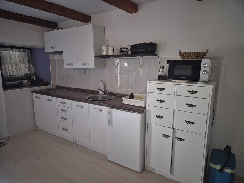 Nowoczesna biała kuchnia z małymi szafkami i półkami.