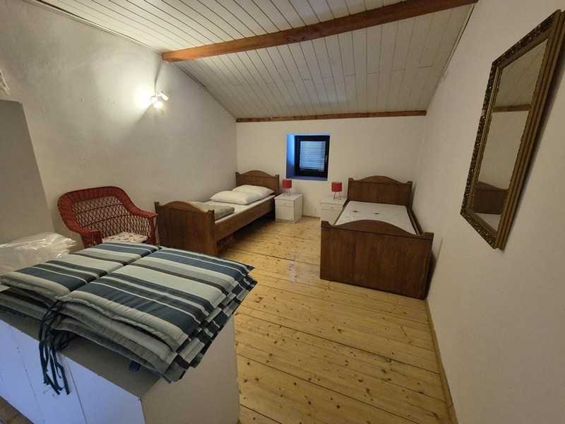 Sypialnia z dwoma pojedynczymi łóżkami i prostym umeblowaniem.